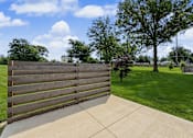 Thumbnail 16 of 34 - A wooden fence in the foreground with a green lawn and trees in the background.