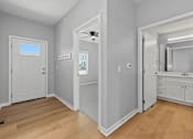 Thumbnail 17 of 53 - A room with a door, a mirror, and a ceiling fan.