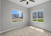 Thumbnail 20 of 53 - A room with a ceiling fan and two windows overlooking a street.