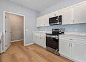 Thumbnail 26 of 53 - A kitchen with white cabinets and a black microwave.
