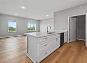Thumbnail 31 of 53 - A kitchen with a large island and wooden floors.