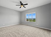 Thumbnail 19 of 53 - A room with a ceiling fan and a window showing a view of the outdoors.