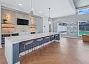 Thumbnail 43 of 53 - A modern kitchen with a long white island and red barstools.