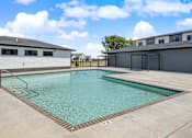 Thumbnail 34 of 53 - A swimming pool with a metal ladder and a building in the background.
