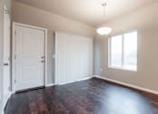 Thumbnail 22 of 30 - A room with a white door, a window with blinds, and a wooden floor. at Danamere Village, Carlisle, Iowa
