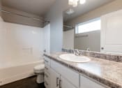 Thumbnail 18 of 30 - A bathroom with a toilet, sink, and a window. at Danamere Village, Carlisle, IA