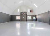 Thumbnail 41 of 66 - A spacious indoor basketball court with a white floor and walls.