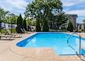 Thumbnail 34 of 66 - A blue swimming pool surrounded by trees and chairs.