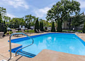 Thumbnail 64 of 66 - A blue swimming pool surrounded by trees and a fence.