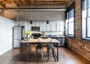 Thumbnail 10 of 99 - A kitchen with a table and chairs in the middle of the room.at Plant 1 Lofts, N. Newton, IA  