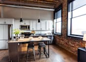 Thumbnail 11 of 99 - A kitchen with a table and chairs in front of a brick wall.at Plant 1 Lofts, Iowa, 50208