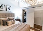 Thumbnail 15 of 99 - A bedroom with a bed, pillows, and a washing machine in the closet.at Plant 1 Lofts, N. Newton, 50208  