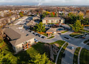 Thumbnail 78 of 90 - An aerial view of a parking lot and buildings with trees in the background at Rosemont Place Apartments, Iowa, 50320