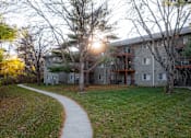 Thumbnail 64 of 90 - A sunlit pathway leads to a building with a balcony at Rosemont Place Apartments, Des Moines, 50320