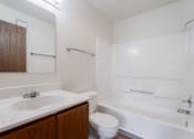 Thumbnail 22 of 90 - A white bathroom with a toilet, sink, and bathtub at Rosemont Place Apartments, Des Moines, Iowa
