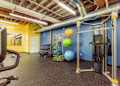 Thumbnail 18 of 25 - A gym with a variety of equipment including a weight machine and a bench press at Spaulding Lofts Apartments, IA, 50112