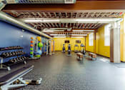 Thumbnail 22 of 25 - A gym with a variety of equipment including weights and exercise machines at Spaulding Lofts Apartments, IA, 50112