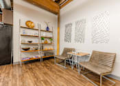 Thumbnail 12 of 25 - A kitchen with a refrigerator, a table with two chairs, and shelves with various items at Spaulding Lofts Apartments, Iowa