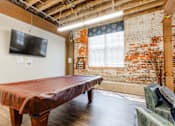 Thumbnail 15 of 25 - A room with a red table and a brick wall at Spaulding Lofts Apartments, Grinnell, IA, 50112