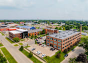 Thumbnail 24 of 25 - A large building complex with a parking lot in front at Spaulding Lofts Apartments, Grinnell, IA