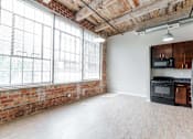 Thumbnail 5 of 25 - A kitchen area with a brick wall and wooden flooring at Spaulding Lofts Apartments, Grinnell, Iowa