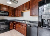 Thumbnail 1 of 25 - A kitchen with wooden cabinets and black appliances at Spaulding Lofts Apartments, Grinnell, IA, 50112