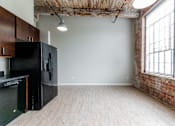 Thumbnail 3 of 28 - A kitchen with a black fridge and wooden cabinets.