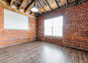 Thumbnail 7 of 25 - A room with a brick wall and wooden floor at Spaulding Lofts Apartments, Grinnell, Iowa