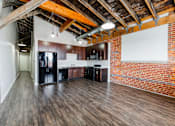 Thumbnail 2 of 28 - A kitchen area with wooden floors and a brick wall.