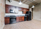 Thumbnail 9 of 28 - A kitchen with wooden cabinets and black appliances.