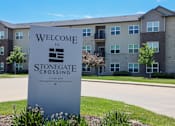 Thumbnail 53 of 57 - A welcome sign for Stonegate Crossing in front of apartment buildings.