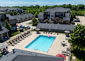 Thumbnail 27 of 57 - A large swimming pool surrounded by lounge chairs and umbrellas in a residential area.