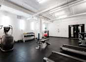 Thumbnail 38 of 50 - A gym with a treadmill, weights, and exercise equipment.