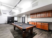 Thumbnail 34 of 50 - A pool table is in the middle of a room with a black chair and a TV.