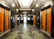 Thumbnail 41 of 50 - A long hallway with marble floors and wood doors.