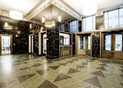 Thumbnail 40 of 50 - A hallway with marble floors and wooden doors.