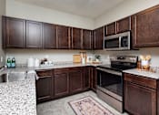 Thumbnail 14 of 31 - modern kitchen with stainless steel appliances and wood cabinets at Lake Shore Apartments, Ankeny, IA