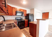 Thumbnail 22 of 56 - Kitchen with brown wooden cabinets at Meadowlark Place Apartments, Grimes, IA,  50111