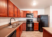 Thumbnail 20 of 56 - Kitchen with brown cabinets at Meadowlark Place Apartments, Grimes