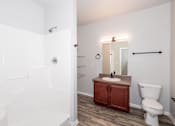 Thumbnail 17 of 56 - A white bathroom with a toilet, sink, and mirror at Meadowlark Place Apartments, Grimes, Iowa