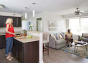 Thumbnail 3 of 56 - A woman in a red top is standing in a kitchen at Meadowlark Place Apartments, Grimes, IA