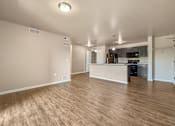 Thumbnail 4 of 47 - A spacious living room with wooden flooring and a kitchen area in the background at Melbourne Apartments in Des Moines, Iowa 50320.