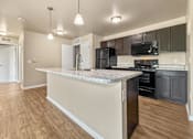 Thumbnail 1 of 47 - A kitchen with a marble countertop and black appliances at Melbourne Apartments in Des Moines, Iowa 50320.