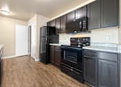 Thumbnail 7 of 47 - A kitchen with black appliances and wooden floors at Melbourne Apartments in Des Moines, Iowa 50320.