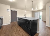 Thumbnail 3 of 47 - A kitchen at Melbourne Apartments in Des Moines, Iowa 50320 with black cabinets and hardwood flooring.