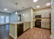 Thumbnail 6 of 12 - A kitchen with wooden floors and a mix of white and dark cabinetry.