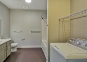Thumbnail 7 of 12 - A small bathroom with a washer and dryer.