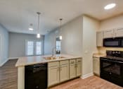 Thumbnail 4 of 12 - A kitchen with a black oven and white cabinets.
