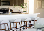 Thumbnail 26 of 69 - a view of a kitchen with bar stools and a living room with a counter at Converge NW, Waukee Iowa  