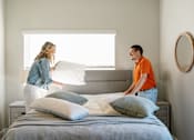 Thumbnail 24 of 69 - a man and a woman standing over a bed with pillows at Converge NW, Waukee, 50263  